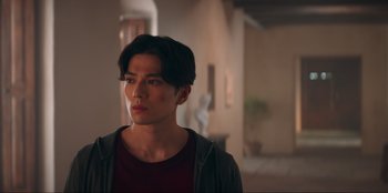 Movie still from “Knights of the Zodiac” (2023), directed by Tomasz Baginski – A young man in a red shirt is looking to his left; Close Up shot, Low angle