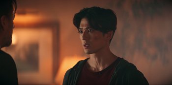 Movie still from “Knights of the Zodiac” (2023), directed by Tomasz Baginski – A man with short black hair is looking to his left; Close Up shot, Over the shoulder angle