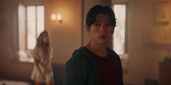 Movie still from “Knights of the Zodiac” (2023), directed by Tomasz Baginski – A man standing in front of a woman in a room; Medium shot, Over the shoulder angle