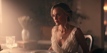 Movie still from “Knights of the Zodiac” (2023), directed by Tomasz Baginski – A beautiful young lady sitting at a dinner table; Close Up shot, Low angle