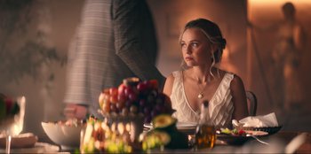 Movie still from “Knights of the Zodiac” (2023), directed by Tomasz Baginski – A woman sitting at a table with a bunch of fruit; Medium shot, Over the shoulder angle