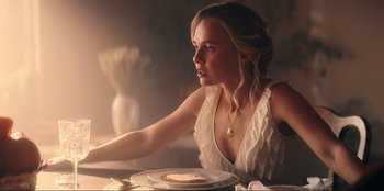 Movie still from “Knights of the Zodiac” (2023), directed by Tomasz Baginski – A beautiful young lady sitting at a table with a plate; Medium shot, Over the shoulder angle
