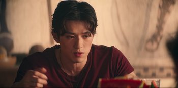 Movie still from “Knights of the Zodiac” (2023), directed by Tomasz Baginski – A man in a red shirt is looking at a book; Close Up shot, Over the shoulder angle