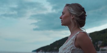 Movie still from “Knights of the Zodiac” (2023), directed by Tomasz Baginski – A beautiful young lady standing on top of a beach; Close Up shot, Low angle
