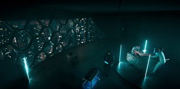 Movie still from “Knights of the Zodiac” (2023), directed by Tomasz Baginski – A man standing in a room lit up with lights; Extreme Wide shot, High angle
