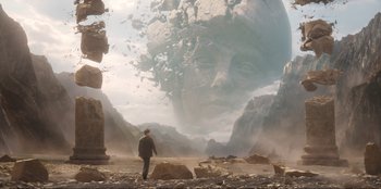 Movie still from “Knights of the Zodiac” (2023), directed by Tomasz Baginski – A man standing in front of an image of a giant head; Extreme Wide shot, Low angle