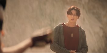 Movie still from “Knights of the Zodiac” (2023), directed by Tomasz Baginski – A young man is standing in front of a camera; Medium shot, Over the shoulder angle