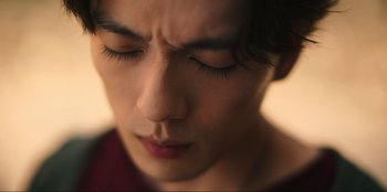 Movie still from “Knights of the Zodiac” (2023), directed by Tomasz Baginski – A person with closed eyes; Extreme Close Up shot, Low angle