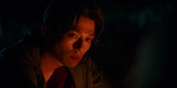 Movie still from “Knights of the Zodiac” (2023), directed by Tomasz Baginski – A man with long brown hair is looking at the camera; Close Up shot, Low angle