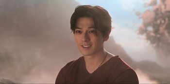 Movie still from “Knights of the Zodiac” (2023), directed by Tomasz Baginski – A young man with long dark brown hair wearing a red shirt; Close Up shot, Over the shoulder angle