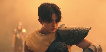 Movie still from “Knights of the Zodiac” (2023), directed by Tomasz Baginski – A man holding a bird in his arms; Medium shot, Low angle