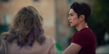 Movie still from “Knights of the Zodiac” (2023), directed by Tomasz Baginski – A man with long black hair is looking at a woman; Medium shot, Over the shoulder angle