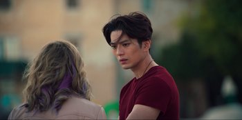 Movie still from “Knights of the Zodiac” (2023), directed by Tomasz Baginski – A young man in a red shirt is looking at a woman; Close Up shot, Over the shoulder angle