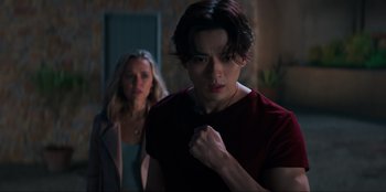 Movie still from “Knights of the Zodiac” (2023), directed by Tomasz Baginski – A man and a woman standing next to each other in a room; Medium shot, Low angle