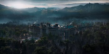 Movie still from “Knights of the Zodiac” (2023), directed by Tomasz Baginski – An aerial view of a building in the middle of a forest; Extreme Wide shot, High angle