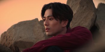 Movie still from “Knights of the Zodiac” (2023), directed by Tomasz Baginski – A man with long black hair wearing a red cape; Close Up shot, Low angle