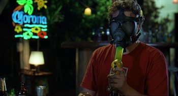 Movie still from “Knocked Up” (2007), directed by Judd Apatow – A man wearing a gas mask holding a bottle of alcohol; Medium shot, High angle