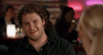 Movie still from “Knocked Up” (2007), directed by Judd Apatow – A man with curly brown hair smiling for the camera; Close Up shot, Over the shoulder angle
