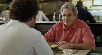 Movie still from “Knocked Up” (2007), directed by Judd Apatow – A man sitting at a table in front of a plate of food; Close Up shot, Over the shoulder angle
