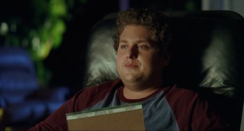 Movie still from “Knocked Up” (2007), directed by Judd Apatow – A person sitting in a chair holding a book; Close Up shot, Over the shoulder angle
