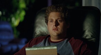 Movie still from “Knocked Up” (2007), directed by Judd Apatow – A person sitting in a chair holding a book; Close Up shot, Over the shoulder angle