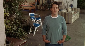 Movie still from “Knocked Up” (2007), directed by Judd Apatow – A man standing in front of a table and chairs; Medium shot, Over the shoulder angle
