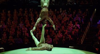 Movie still from “Knocked Up” (2007), directed by Judd Apatow – Two men are performing aerial acrobatics in front of an audience; Wide shot, Low angle