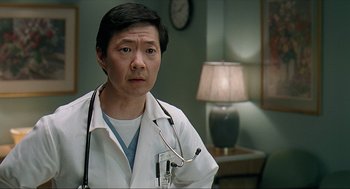 Movie still from “Knocked Up” (2007), directed by Judd Apatow – A man wearing a white lab coat and stethoscope in a room; Close Up shot, Low angle