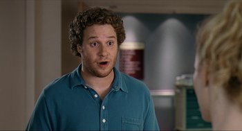 Movie still from “Knocked Up” (2007), directed by Judd Apatow – A man with curly hair is standing in a room; Close Up shot, High angle
