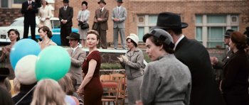 Movie still from “Knowing” (2009), directed by Alex Proyas – A group of people standing in front of a brick building; Medium shot, Over the shoulder angle