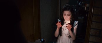 Movie still from “Knowing” (2009), directed by Alex Proyas – A young girl is holding her hands up in the dark; Close Up shot, High angle