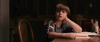 Movie still from “Knowing” (2009), directed by Alex Proyas – A boy sitting at a table with his hand on his chin; Close Up shot, High angle