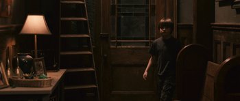 Movie still from “Knowing” (2009), directed by Alex Proyas – A young boy standing in front of an open door; Wide shot, High angle