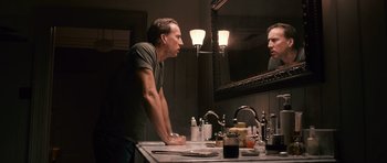 Movie still from “Knowing” (2009), directed by Alex Proyas – A man standing in front of a bathroom mirror looking at himself in the mirror; Close Up shot, Low angle