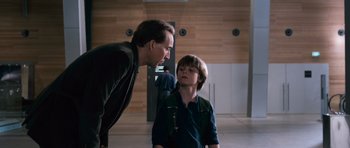 Movie still from “Knowing” (2009), directed by Alex Proyas – A man and a boy are talking in a room; Medium shot, Over the shoulder angle