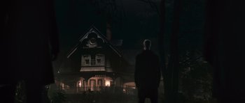 Movie still from “Knowing” (2009), directed by Alex Proyas – A man standing in front of a house at night; Wide shot, Low angle