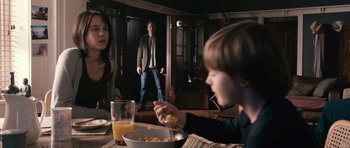 Movie still from “Knowing” (2009), directed by Alex Proyas – A man and a woman and a child are eating cereal; Medium shot, Over the shoulder angle