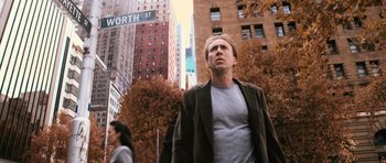 Movie still from “Knowing” (2009), directed by Alex Proyas – A man standing in front of a building in a city; Medium shot, Over the shoulder angle