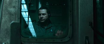 Movie still from “Knowing” (2009), directed by Alex Proyas – A man with a headset in front of a window; Close Up shot, Low angle