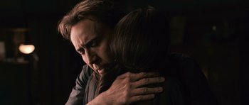 Movie still from “Knowing” (2009), directed by Alex Proyas – A man and a woman hugging in a dark room; Close Up shot, Over the shoulder angle