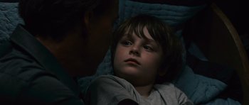 Movie still from “Knowing” (2009), directed by Alex Proyas – A young boy laying in a bed with a blanket; Close Up shot, Overhead angle