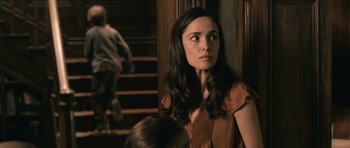 Movie still from “Knowing” (2009), directed by Alex Proyas – A woman standing in front of stairs with a child; Medium shot, Over the shoulder angle