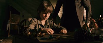 Movie still from “Knowing” (2009), directed by Alex Proyas – A young boy is playing with a wooden toy; Medium shot, High angle