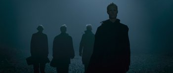 Movie still from “Knowing” (2009), directed by Alex Proyas – Three people are walking in the dark in the fog; Medium shot, Low angle