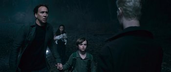 Movie still from “Knowing” (2009), directed by Alex Proyas – A group of people standing in the woods at night holding hands; Medium shot, Over the shoulder angle