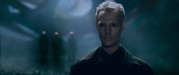 Movie still from “Knowing” (2009), directed by Alex Proyas – A man with blonde hair is standing in the dark; Close Up shot, Low angle