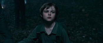 Movie still from “Knowing” (2009), directed by Alex Proyas – A young boy is standing in the dark; Close Up shot, Low angle