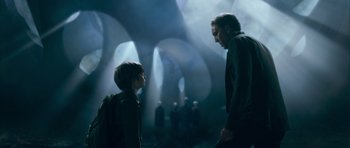 Movie still from “Knowing” (2009), directed by Alex Proyas – A man and a boy are standing next to each other; Medium shot, Low angle