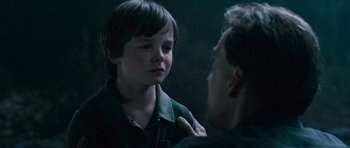Movie still from “Knowing” (2009), directed by Alex Proyas – A young boy is crying as a man looks on; Close Up shot, Over the shoulder angle
