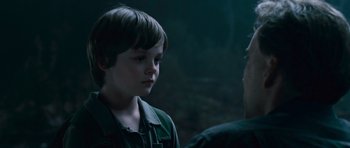 Movie still from “Knowing” (2009), directed by Alex Proyas – A young boy talking to a man in a dark forest; Close Up shot, Over the shoulder angle